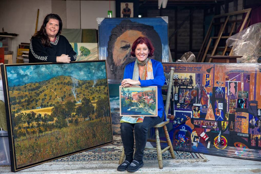 LEGACY: Rachel Carroll (right), with her sister Jemima Carroll, in her northern beaches home with paintings by their well known artist father Patrick Carroll. Picture: DALLAS KILPONEN